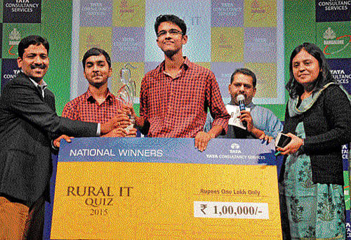 Tata Consultancy Services Bengaluru Centre Head E S Chakravarthy and IT, BT, Science and Technology Department Director Tanusree Deb Burma present a cheque for Rs 1 lakh to the winners of the Rural IT Quiz 2015, Geeve and Karthik Rao, of Little Rock Indian School, Udupi, in Bengaluru on Tuesday. Quizmaster Giri Balasubramaniam is also seen. DH&#8200;photo