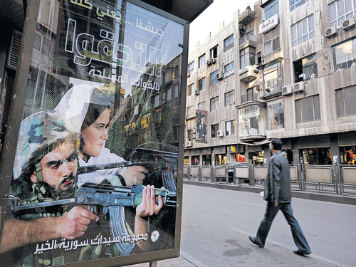 ready to strike: A man walks near an advertisement calling on people to join the Syrian military forces, in Damascus, Syria on November 12, 2015. The text on the billboard reads in Arabic: