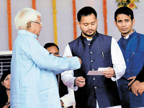 power play: RJD chief Lalu Prasad with his wife Rabri Devi and sons during the swearing-in ceremony in Patna on Friday.pti