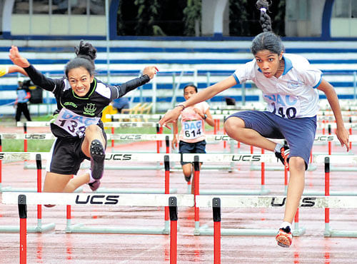 ON SONG Tejasswini G (right) of St Francis Xavier Girls' HS and en route to victory in the 100M hurdles. Jahnavi BG of Soundarya Primary School clinched the1500M gold in the U-15 section at the 27th DAC meet in Bengaluru on Sunday. DH PHOTO