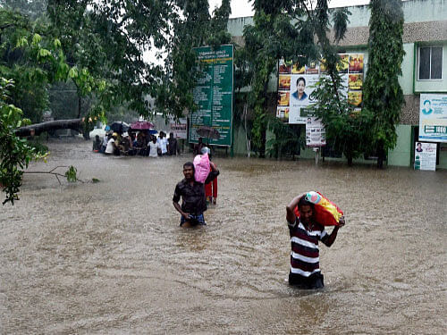 Patients and their care-takers shift from a flooded hospital after heavy rains in Chennai on Tuesday. PTI Photo.