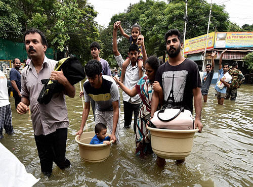 People wade through waterlogged road following heavy rains in Chennai on Wednesday. PTI Photo