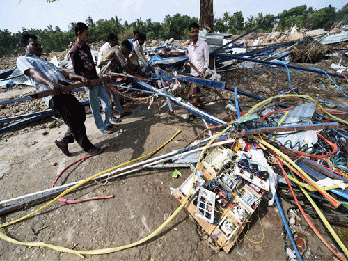 People try to salvage reusable material from their flood damaged Machine on the banks of the Adyar River at Anakaputhur outskirts of Chennai on Monday. PTI Photo.