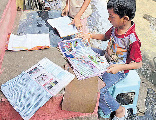 Children look at the remains of their  textbooks in Porur area of Chennai on Tuesday. DH Photo
