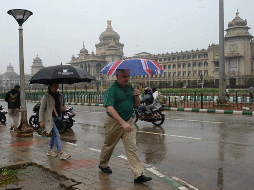 Foreign tourist move in front of the Vidhana Soudha in the drizzle in Bengaluru. DH File Photo.