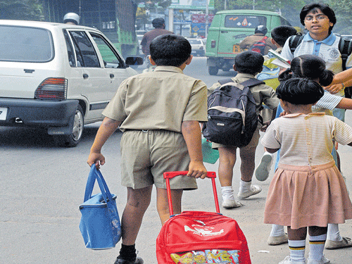 weighed down:  A school boy drags along a trolley bag with his school books on St Mark's Road as he is unable to  carry the heavy bag on his shoulders. DH PHOTO