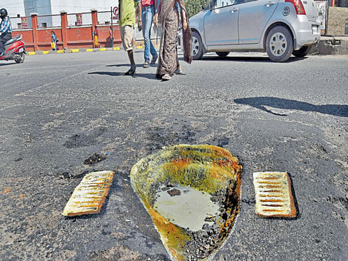 A pothole near Shivajinagar bus stand has been turned into a broken toilet by artist Baadal Nanjundaswamy to draw the attention of the authorities. DH photo