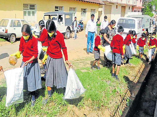 Students clean Sri Omkareshwara Temple premises as part of a cleanliness drive in Madikeri on Monday. DH photo