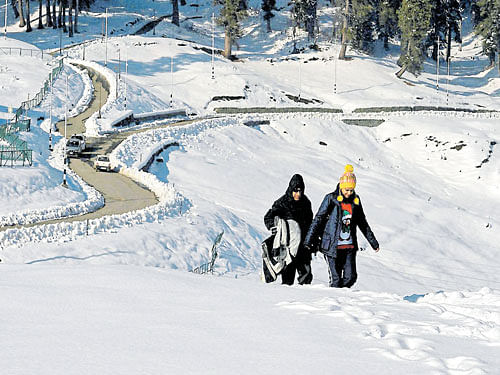 Tourists enjoy a walk at ski resort Gulmarg after fresh snowfall on Tuesday. PTI
