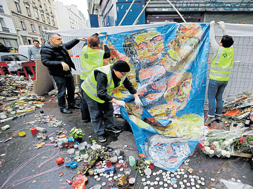 An archival team holds a memorial painting as it collects the notes, poems and drawings left by passers-by at a memorial in front of the "Casa Nostra" pizzeria (right). REUTERS