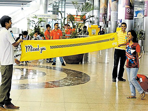 EXCITING The employees of 'Oye Happy' hold up a 15-feet banner at the airport.