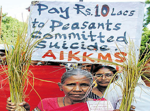 A woman holds farm produce in a protest seeking aid for farmers in Bhubaneswar