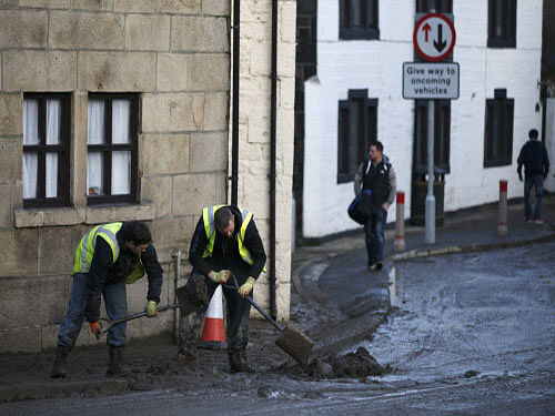 Men clear silt outside a home after flooding in the town of Mytholmroyd, northern England. Reuters photo