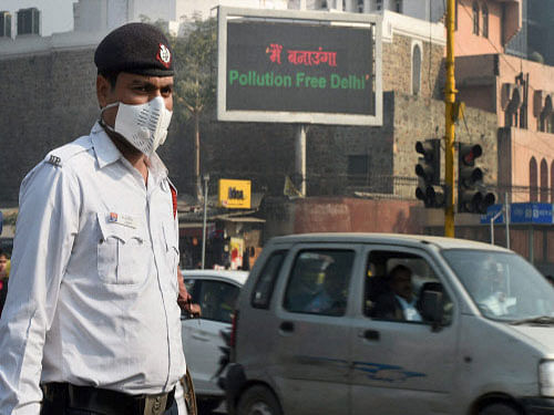 A traffic policeman takes protection against pollution in New Delhi. Delhi Government's ambitious odd-even scheme to curb pollution in the national capital which was rolled out today garnered mixed response from the commuters with some of them lauding it for the 'futuristic approach' and a few dubbing it 'impractical'. PTI photo