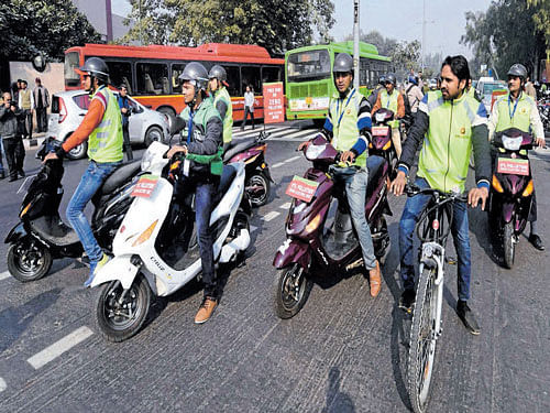 Volunteers offer free rides on e-bikes to commuters after the trial of odd-even scheme came into effect in New Delhi on Friday. PTI