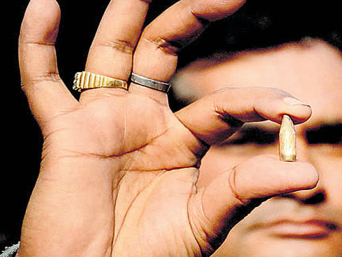 A man shows a bullet that fell in the market of Dhaki Chowk during the encounter. PTI