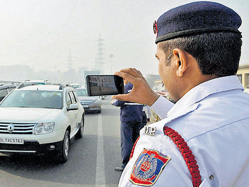 A traffic cop clicks pictures during implementation of odd- even rule on the Delhi-Gurgaon expressway on Monday. PTI