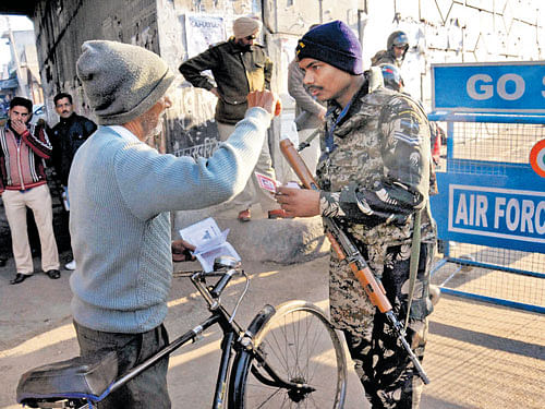 on high alert: A security personnel checks the identity of a person near the Indian Air Force base where an operation against militants was carried out. PTI