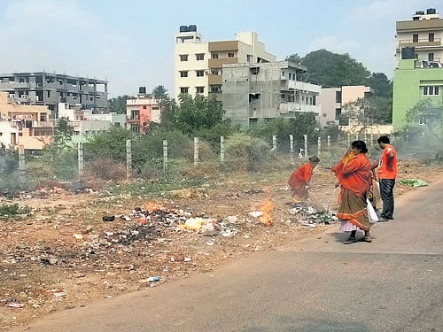 Pourakarmikas set a heap of garbage on fire in Subramanyapura on Friday. DH Photo