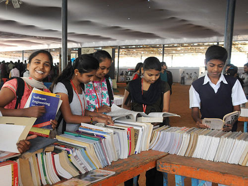 People browsing the books at the 'Pustaka Parishe' a book fair to build reading habits and reuse of old book for free, organised by the 'Shrushthi' Ventures at Basawangudi National college grounds in Bengaluru on Saturday. DH photo