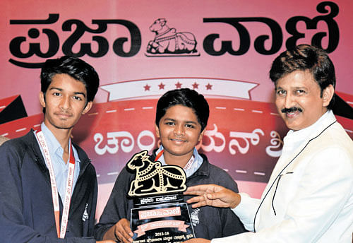Actor Ramesh Aravind gives away winners trophy to Abhinav and Pranav of Presidency School (Bengaluru South) who emerged champions in Prajavani Quiz competition for high school students at Jnana Jyothi Auditorium in the City on Saturday. dh photo