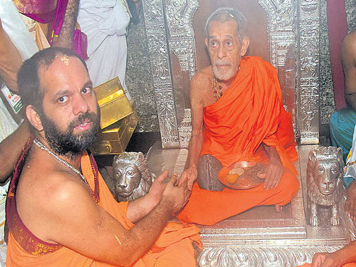 in transition: Pejawar seer Vishweshatheertha Swami ascends the Sarvajna Peetha at the Krishna Mutt in Udupi as part of the Paryaya celebrations in the wee hours of Monday. Outgoing Paryaya seer Vidyavallabhatheertha Swami of Kaniyur Mutt and others look on. DH&#8200;PHOTO