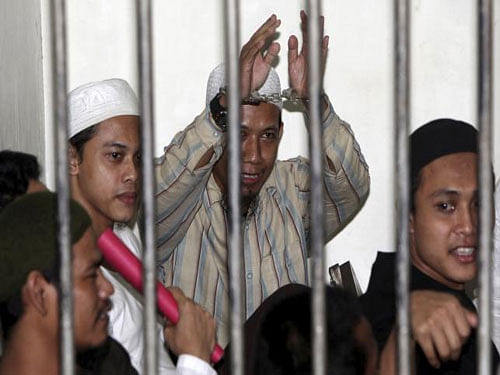 Radical Muslim cleric Aman Abdurrahman (C), also known as Oman Rochman, raises his hands in a holding cell as he waits with other militants for their trial in Jakarta, in this August 26, 2010 Reuters file photo