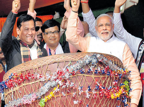 STARTING WITH A BANG: Prime Minister Narendra Modi, along with Union Minister and Assam BJP state president Sarbananda Sonowal, beats a 'Maadol', the traditional drum of tea tribes, at a public rally in Assamon Friday. PTI