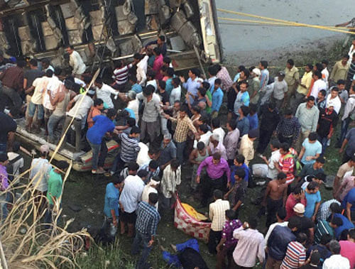 People carry out rescue work after a state transport bus fell off a bridge into the Purna river in Navsari on Friday. PTI Photo