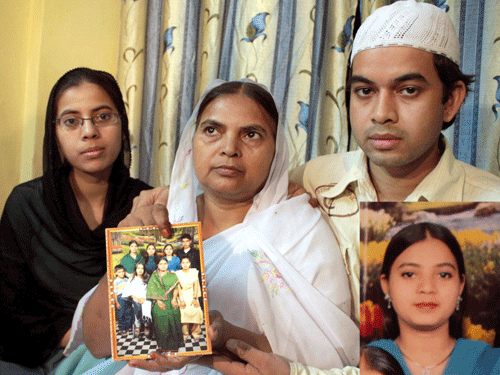 Shamima Kausar, mother of Ishrat Jahan (inset), holds a group photo of the family while standing with her daughter and son in Thane, Mumbai. PTI File Photo.
