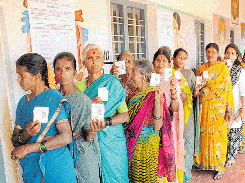 democratic right: Voters display their identity cards as they wait in a queue to cast their votes for the zilla and taluk  panchayath elections at  Bindaganahalli in Bengaluru on Saturday. dh Photo