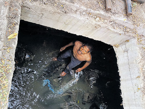 A 40-year-old mentally unstabled man struggles to come out of a manhole after he  accidentally fell into it near Agarahara Dasarahalli on Saturday. DH&#8200;photo