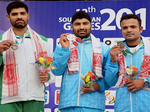 Gold medal winner Gurpreet Singh (center) of India, silver medal winner Ghulam Mustafa Bashir (L) of Pakistan and bronze medal winner Vijay Kumar of India at the presentation ceremony of the 25 metre rapid fire pistol men's individual shooting event at the 12th South Asian Games in Guwahati on Monday. PTI Photo
