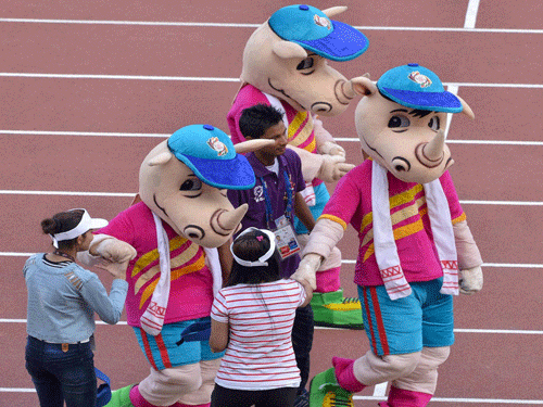 Volunteers shake hands with the official mascot of the 12th South Asian Games, Tikhor, during the closing ceremony at Sarusajai Sports Complex in Guwahati on Tuesday. PTI Photo
