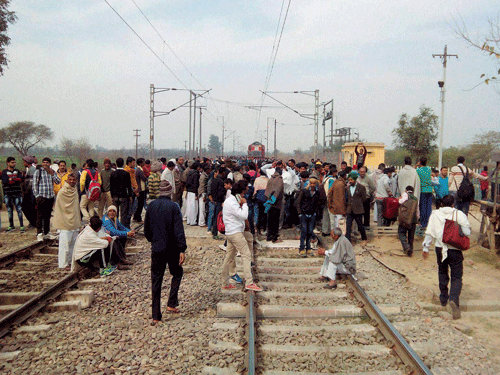 Jat community members block the railway tracks during their agitation for reservation near Rohtak on Monday. PTI Photo.