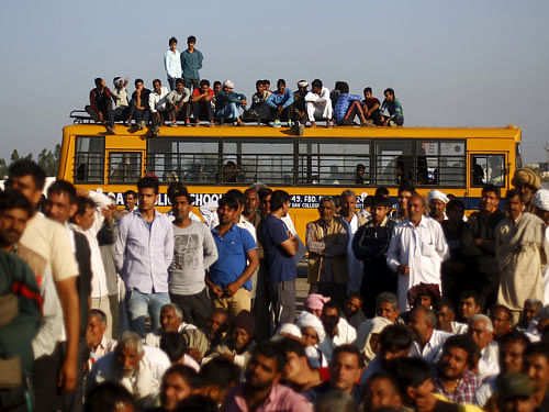 Demonstrators from the Jat community sit on top of a school bus as they block the Delhi-Haryana national highway during a protest at Sampla village in Haryana, India, February 21, 2016. India deployed thousands of troops in a northern state on Sunday to quell protests that have severely hit water supplies to Delhi, a metropolis of more than 20 million, forced factories to close and killed 10 people. REUTERS
