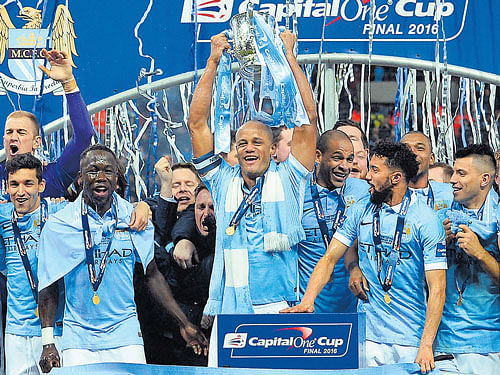 champions Manchester City's captain Vincent Kompany (centre) lifts aloft the League Cup at the Wembley stadium. City beat Liverpool in the final. afp