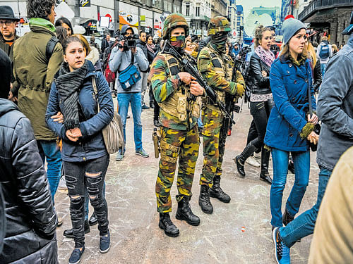 high strung: Soldiers stand guard as people pay their respects to the victims of multiple attacks across Brussels at Place de la Bourse in Brussels. Some Belgians lashed out at a flailing security apparatus and chronically dysfunctional government for abetting the tragedy.  nyt