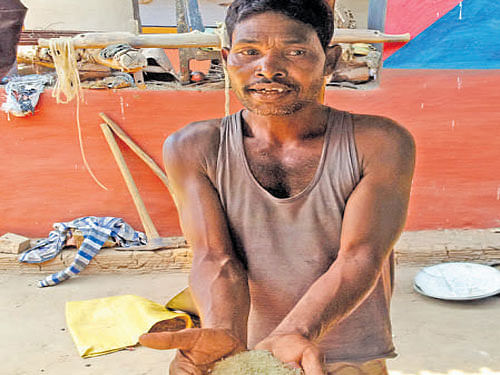 Jyotilal Hansda, a farmer, shows the rice he gets from the local ration shop for Rs 2 a kg. DH Photo