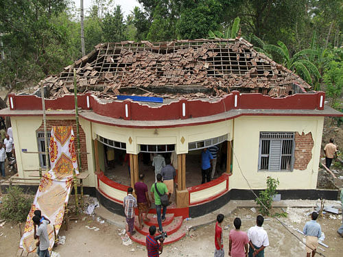 People gather around a damaged section of a temple after a fire broke out at a temple in Kollam in the southern state of Kerala, India, April 10, 2016. A huge fire swept through a temple in India's southern Kerala state early on Sunday (April 10), killing nearly 80 people and injuring over 200 gathered for a fireworks display to mark the start of the local Hindu new year. REUTERS