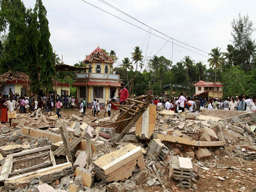People walk past debris after a fire broke out at the Puttingal Devi temple complex in Kollam, Kerala. Conflicting versions are emerging on permission being granted for conduct of fireworks display which led to a major fire in which 102 lives were lost. Reuters photo
