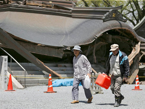 Evacuees walk past the historic Aso Shrine collapsed by powerful earthquakes in Aso, Kumamoto prefecture, Japan, Sunday, April 17, 2016. Two nights of increasingly terrifying earthquakes flattened houses and triggered major landslides in southern Japan. AP/PTI