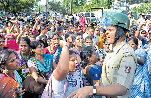 Garment workers confront a policeman on Bannerghatta Road on Monday.  DH&#8200;Photos/Srikanta Sharma R &&#8200;Ranju P