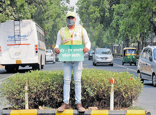 A civil defence volunteer holds a placard for general  awareness during the Odd Even second round on the last day at Janpath Road in New Delhi on Saturday.