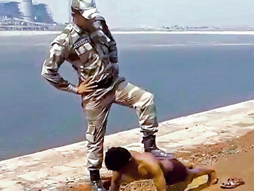 A video grab of a securityman placing his leg on a man as he does push-ups at the NTPC plant at Kudagi, Vijayapura. DH Photo