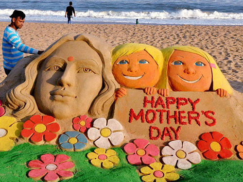 Sand artist Manas Kumar Sahoo creates a sand sculpture on eve of Mother's day in Puri on Saturday. PTI Photo