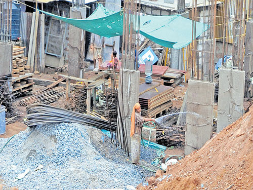 A worker sprinkles water on concrete pillars in Mangaluru on Wednesday. The DC has directed the City  Corporation to issue an order to suspend the ongoing construction activities for the next 15 days. DH&#8200;photo
