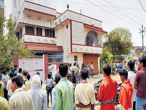 People gather in front of Janata Dal (United) MLC Manorama Devi's house as officials seal the house, in Gaya on Wednesday. Manorama Devi's son Rocky Yadav has been named as an accused in a murder case. PTI
