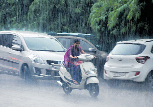 A girl seems to be enjoying the ride in the rain in Davangere on Monday. dh photo