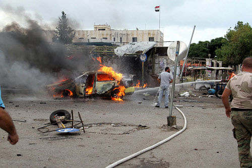 A firefighter tries to put out a fire from a burning car after explosions hit the Syrian city of Tartous. Reuters file photo